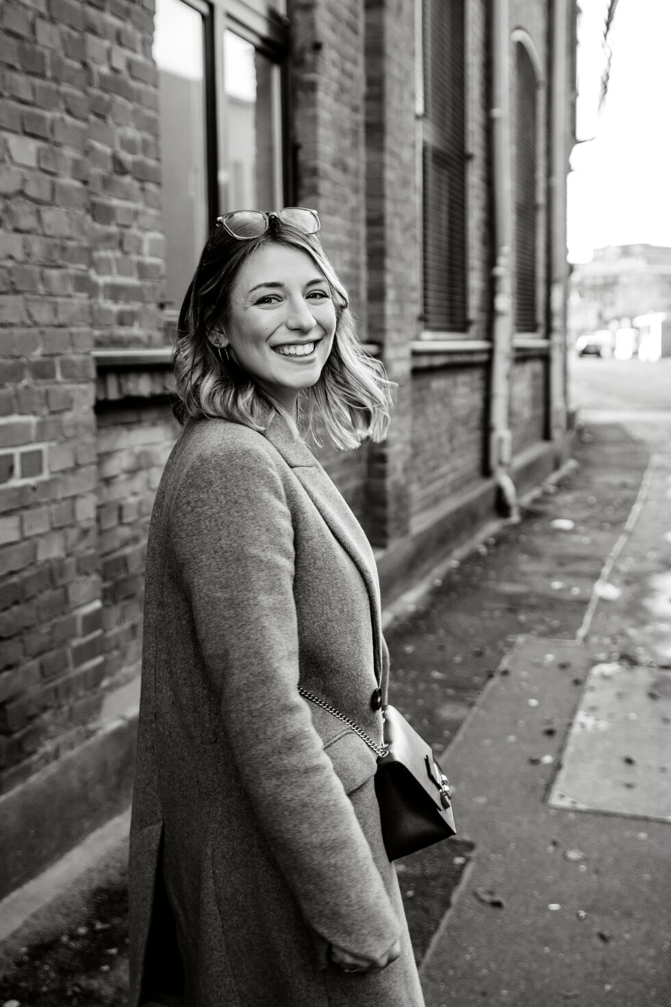 Portrait in schwarz-weiß von einer jungen Frau, die sich umgehend umdreht, und lacht