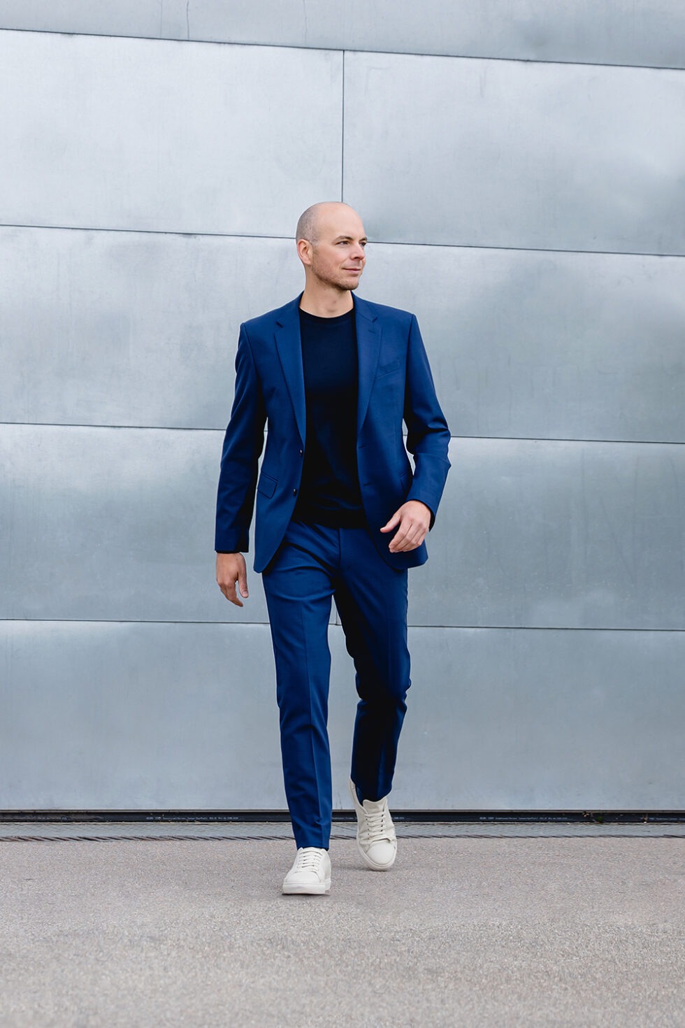 Moderenes Business Foto eines Mannes mit blauem Anzug und schwarzem Oberteil im Gehen