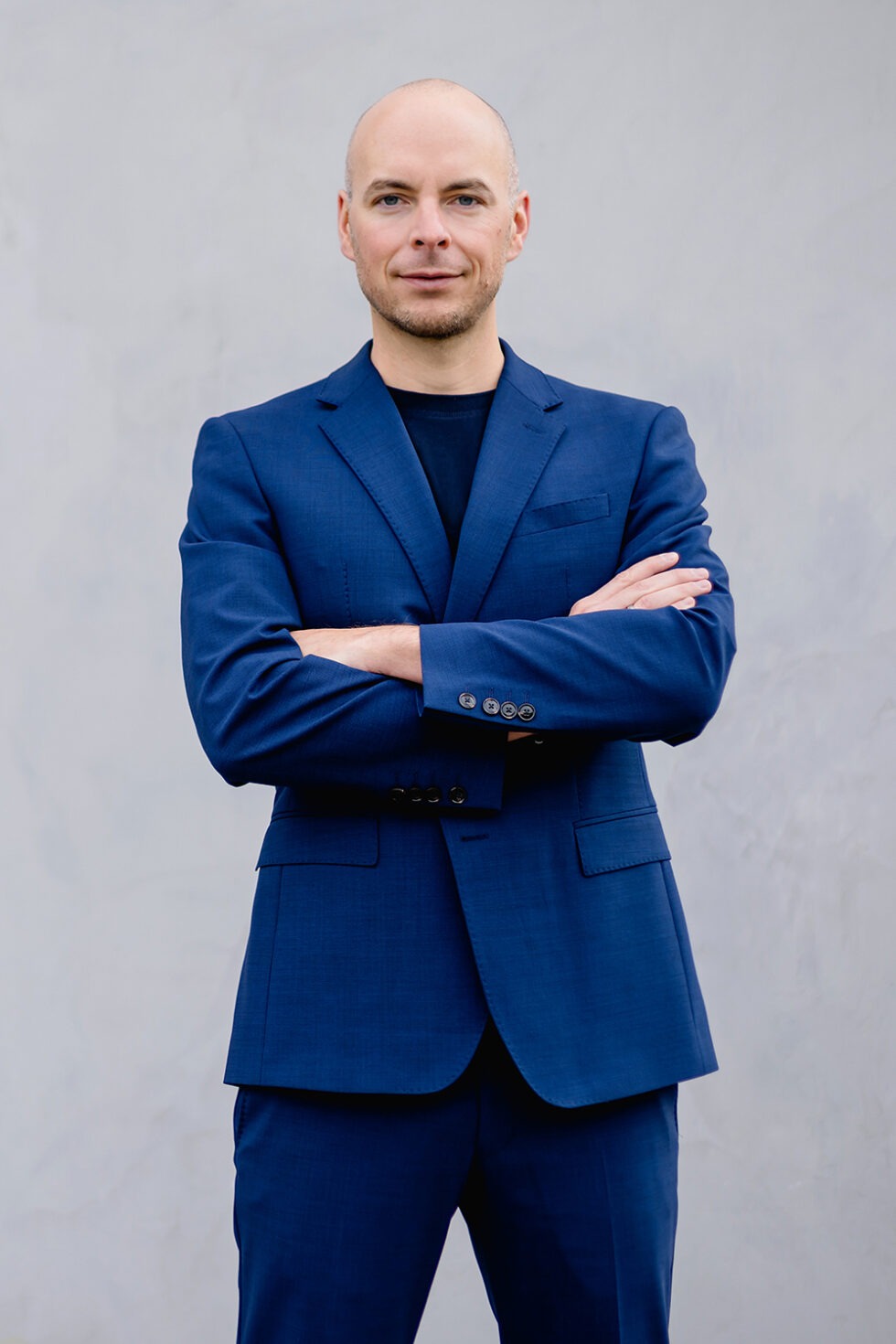 Business Portrait eines Mannes mit blauem Anzug und schwarzem Oberteil