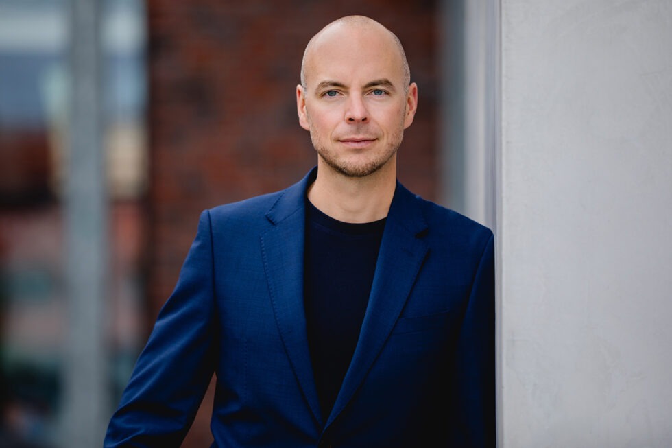 Business Portrait eines Mannes mit blauem Anzug und schwarzem Oberteil