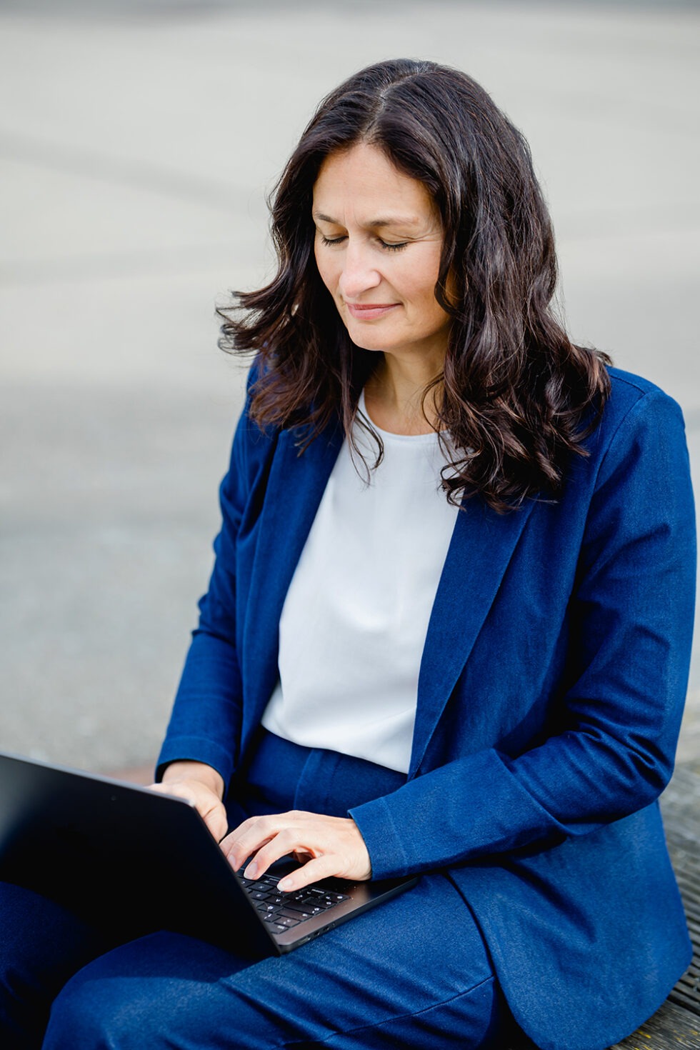 Business Portrait einer Frau mit blauem Anzug mit Laptop
