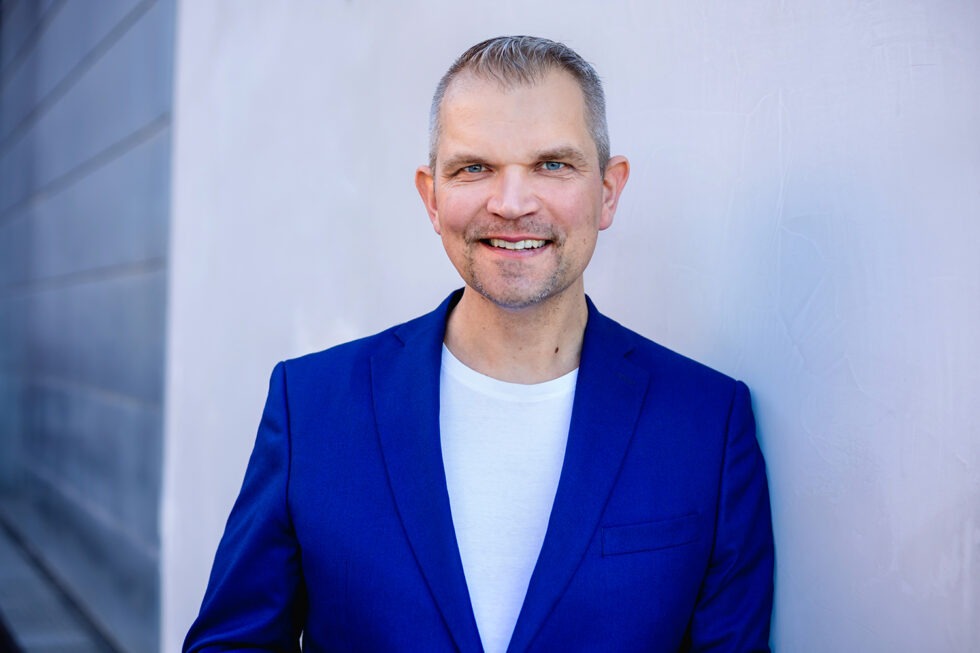 Business Foto eines Mannes mit blauem Anzug vor einer Betonwand